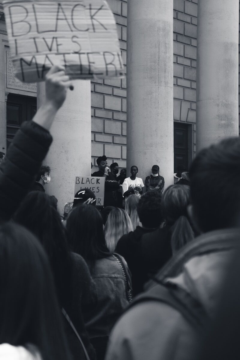 grayscale photo of people raising their hands